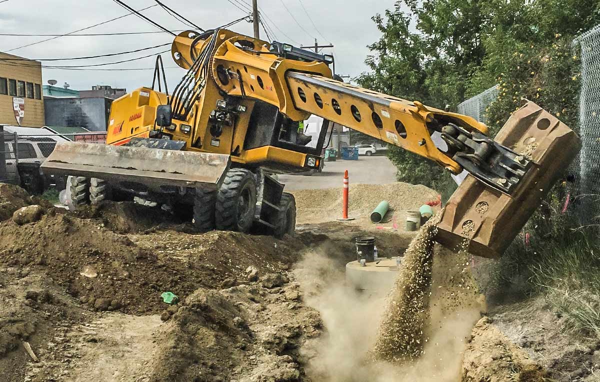 A Gradall Rough Terrain Wheeled Excavator digs on uneven ground.