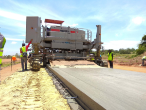 A Power Curber 7700 Multipurpose Slipform Machine being used on a road project.